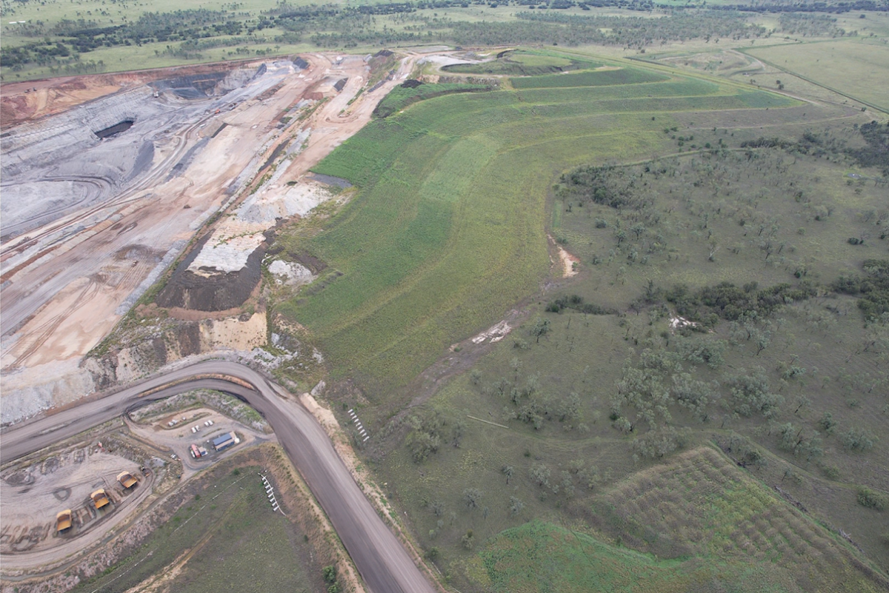 Aerial view of rehabilitated vegetation and surrounding bushland beside mining operations at Meteor Downs South